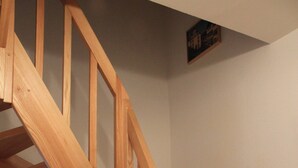 Un escalier en bois, doté d’une rampe et orné d’un petit objet décoratif accroché au mur.