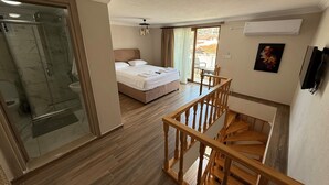 A hotel room with a bed, a shower, a wooden staircase, and a balcony with a view. - Engin Otel (Kandira)