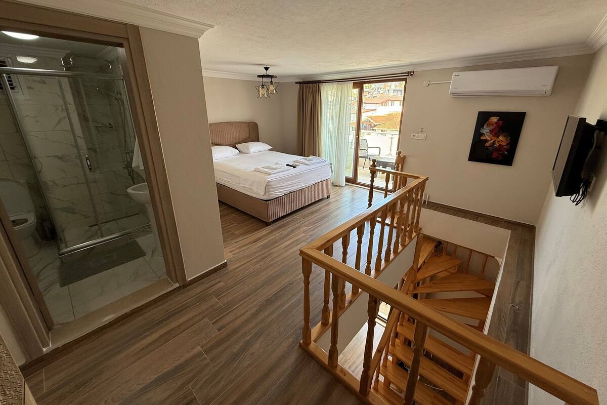Ein Hotelzimmer mit Bett, Dusche, einer Holztreppe und einem Balkon mit Blick.