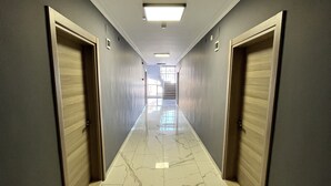 A corridor with marble flooring, grey walls, and wooden doors. - Engin Otel (Kandira)
