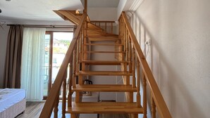 A wooden staircase with a handrail, leading to a room with a bed and a window. - Engin Otel (Kandira)
