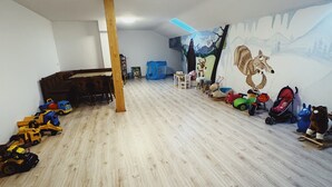 Ein Kinderzimmer mit Holzboden, Wandmalerei und verschiedenen Spielsachen und Spielgeräten.