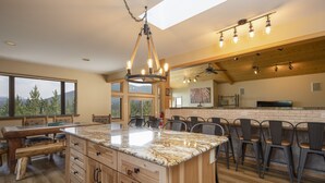 Una cocina amplia con una isla grande, armarios de madera y un techo alto con vigas a la vista.