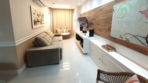 Un salon moderne avec un canapé, un téléviseur et un élément décoratif mural.