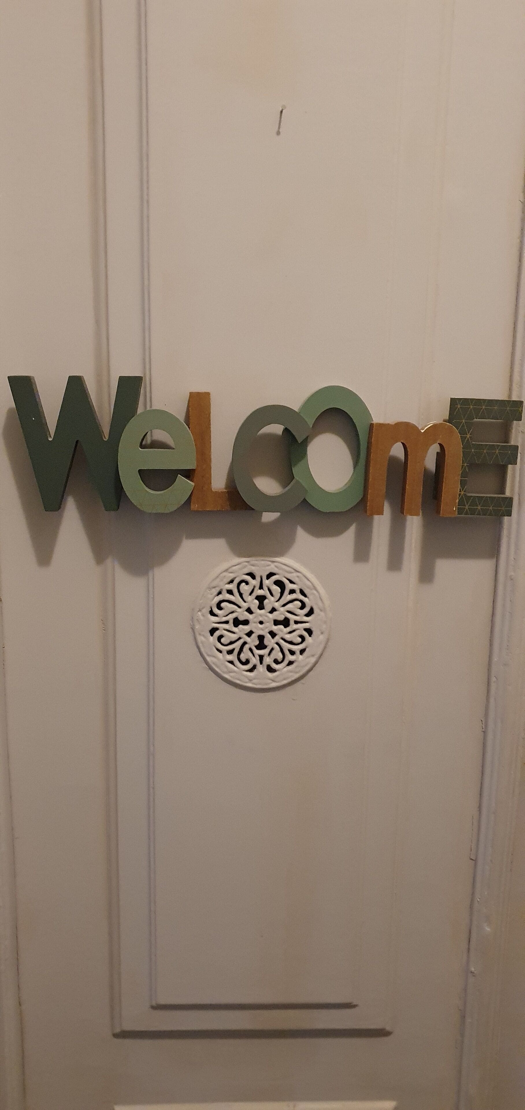 A door with a 'Welcome' sign and a decorative circular pattern.
