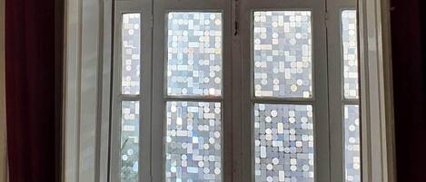 A room with a white door featuring a mosaic pattern, a ceiling light fixture, and a chair.
