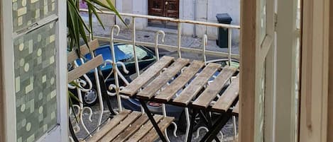 Une vue depuis un balcon doté d’un sol carrelé, d’un banc en bois et d’une plante en pot.