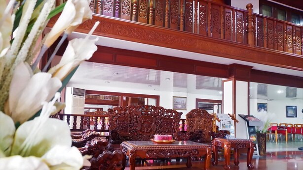 Un hall amplio con techo alto, muebles de madera ornamentados y una barandilla decorativa.