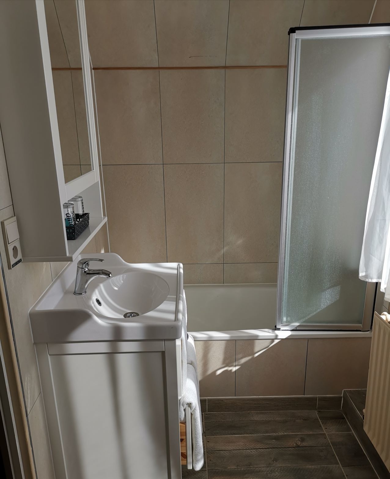 Une salle de bain avec un lavabo blanc, un miroir et une douche.