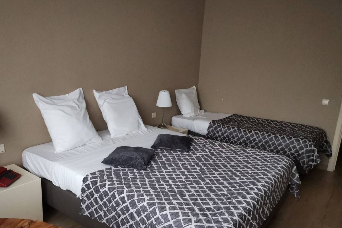 A hotel room with two beds, each with patterned bedding, a bedside lamp, and a nightstand with a telephone.