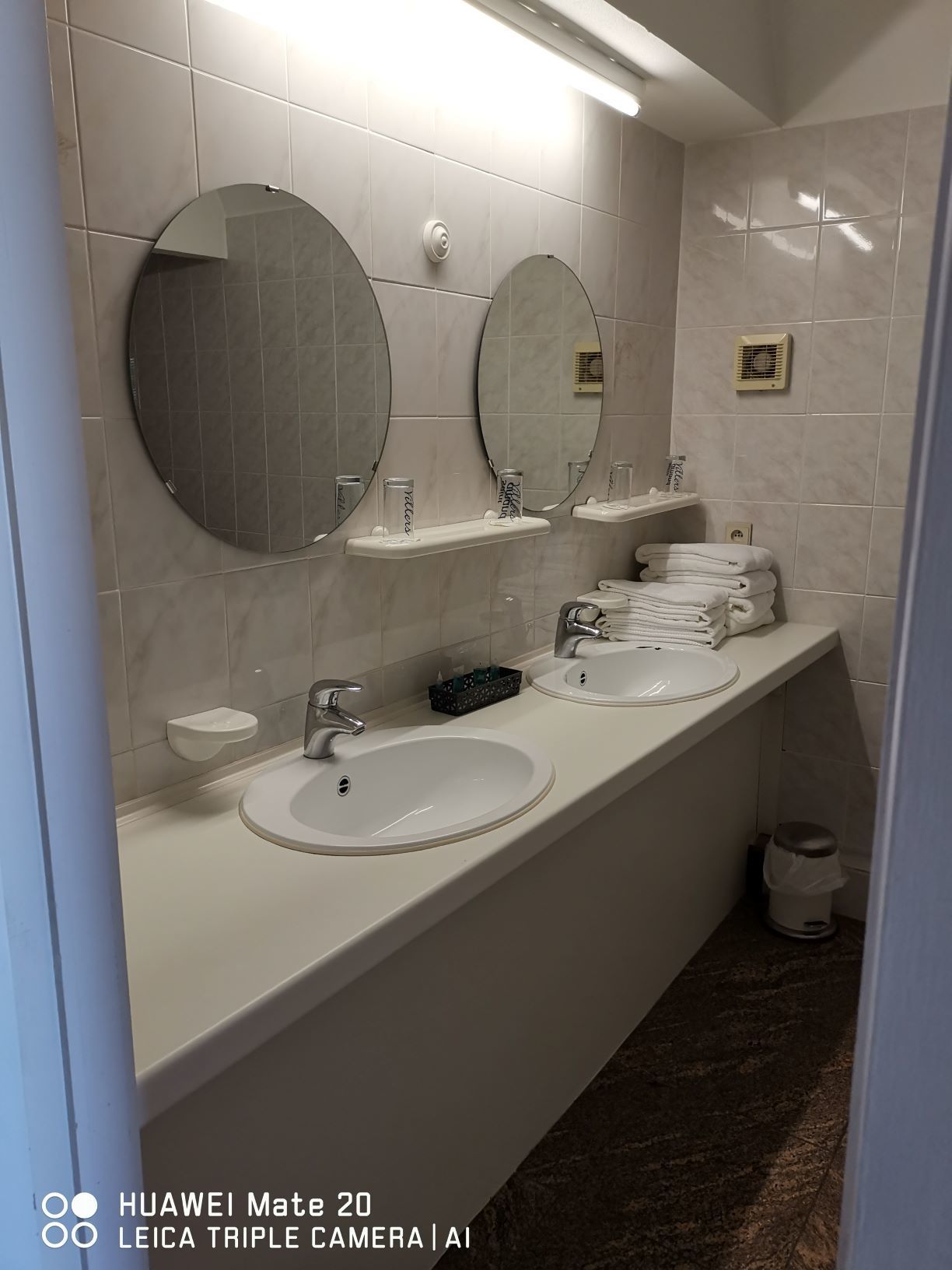 A modern bathroom with two sinks, a mirror, and a towel rack.