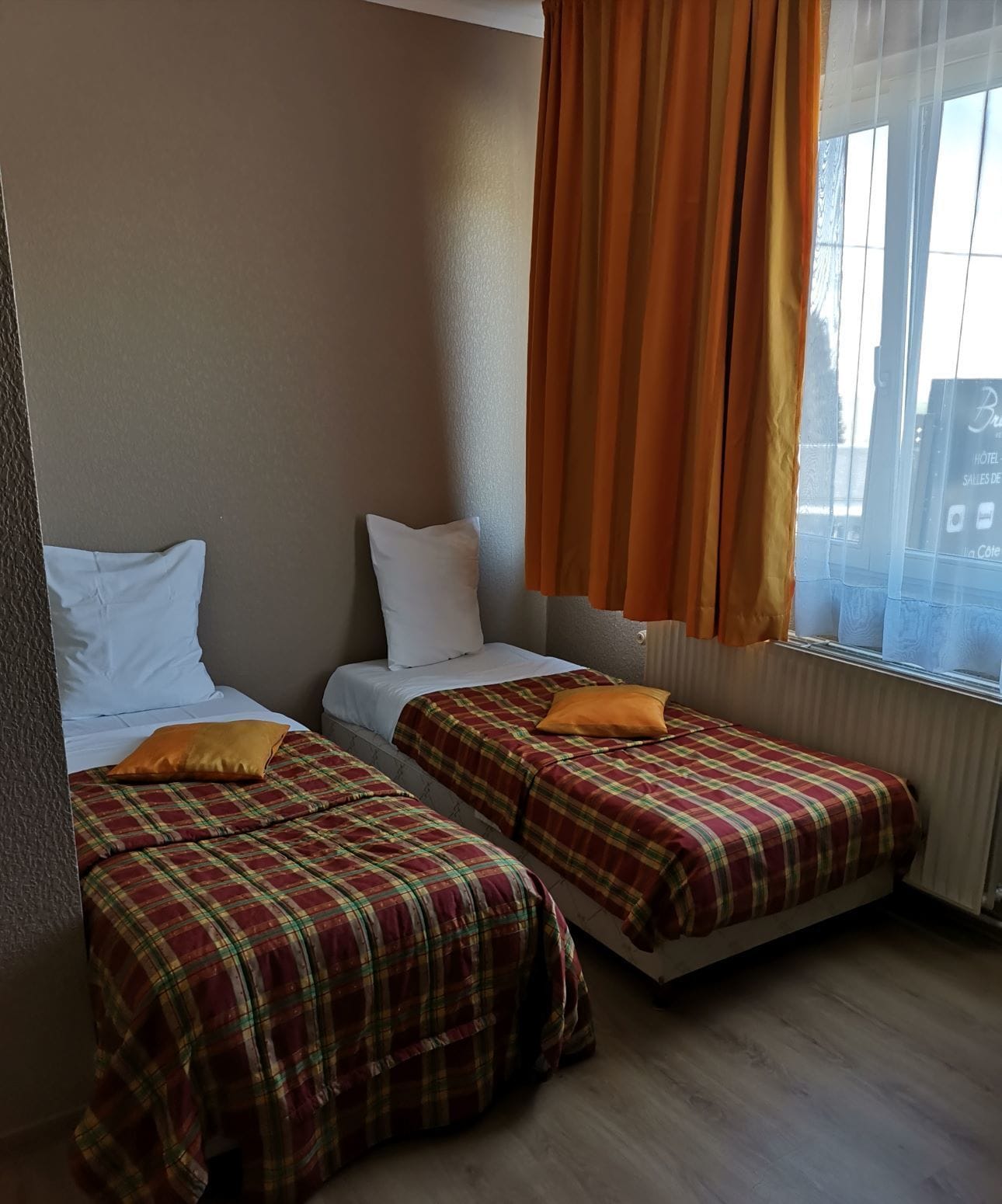 Une chambre avec deux lits, chacun étant recouvert d’une couverture à carreaux et agrémenté d’un oreiller.