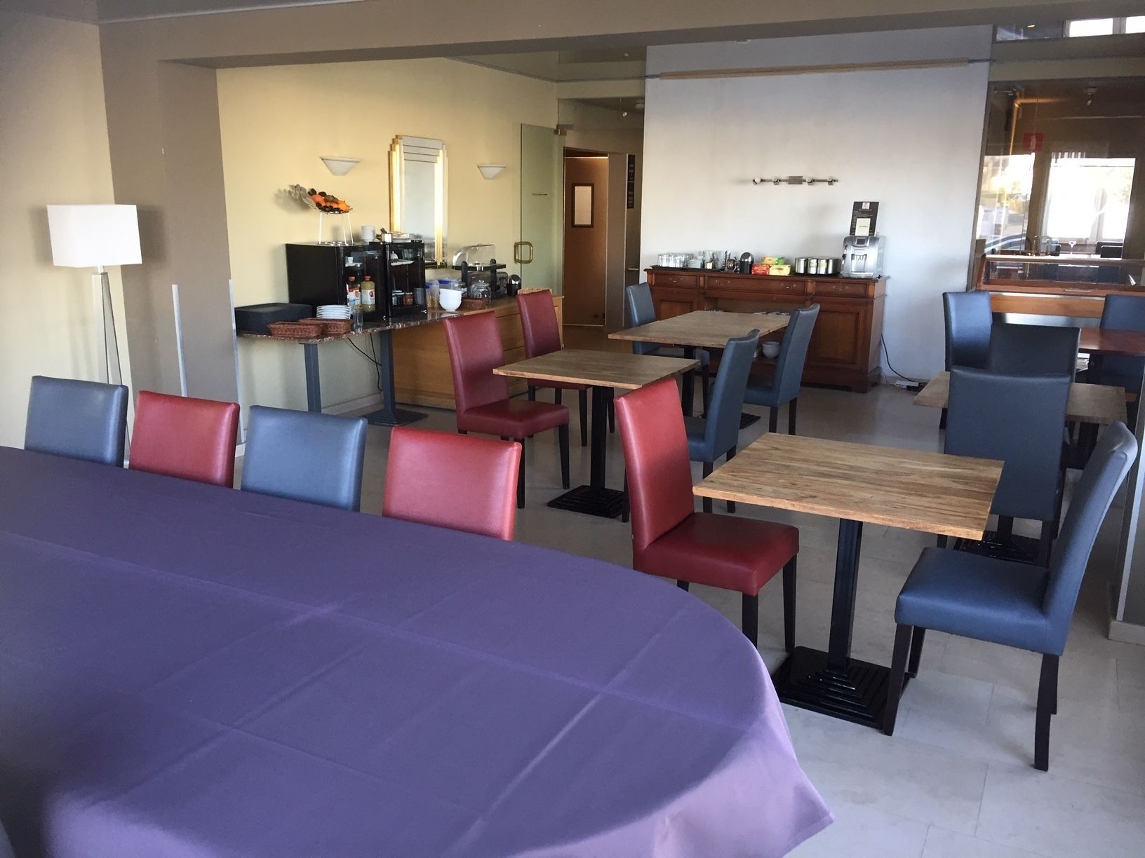 Een eethoek met tafels en stoelen, een koffiehoek en een balie met diverse spullen.