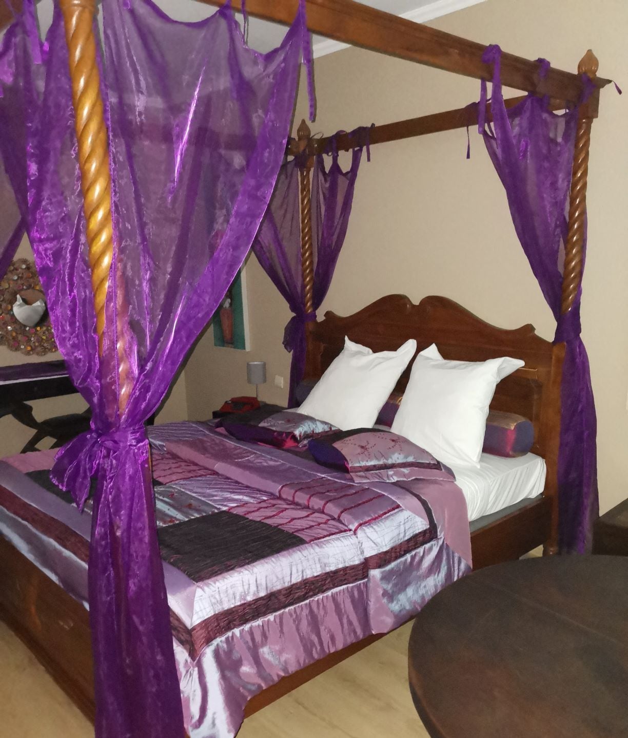 Una cama con dosel de cuatro postes, dos almohadas blancas y una colcha estampada.