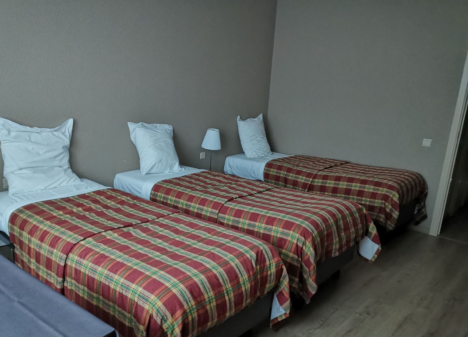 A room with two beds, each with a red plaid bedspread and white pillows.