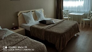 Una camera d'albergo con due letti, una scrivania e una sedia.