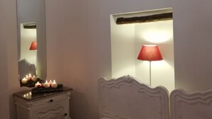 Una camera da letto con un letto, una cassettiera, uno specchio e una lampada a parete.