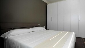 A bedroom with a bed, two pillows, a nightstand, and a wardrobe. - The Residence Galliate (Galliate)