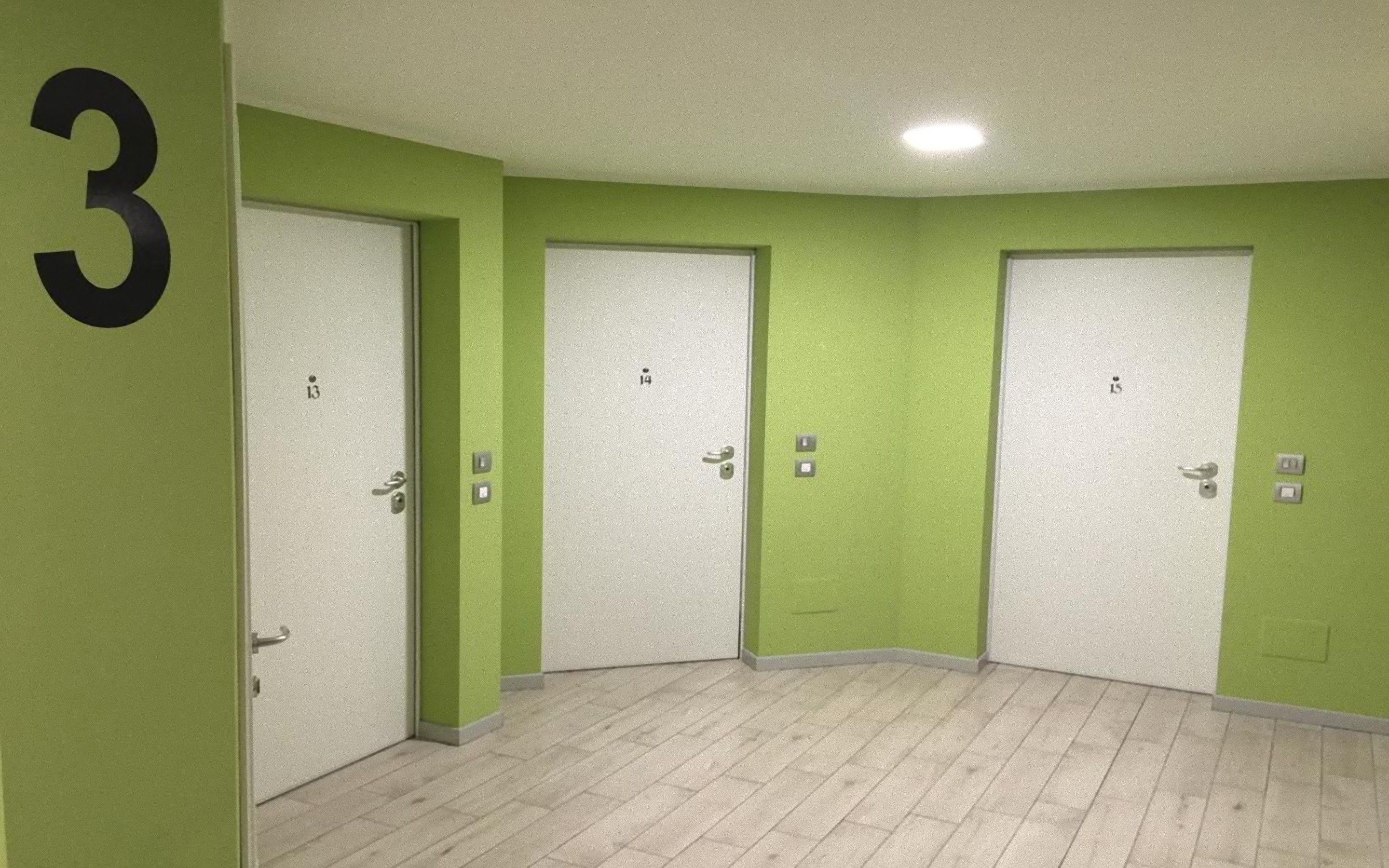 Un ensemble de trois portes dans un couloir, chacune étant marquée d’un numéro sur le mur.