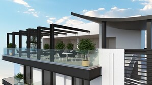 A modern building with a glass balcony, outdoor seating, and greenery. - Maralia Hotel (Nicosia)