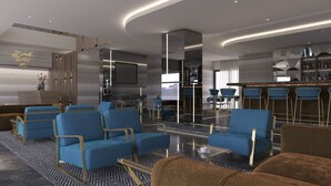 A modern hotel lobby with blue seating, a bar area, and a large TV screen. - Maralia Hotel (Nicosia)