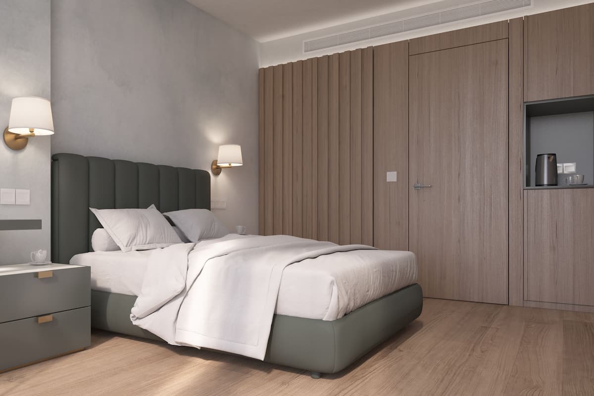A modern bedroom with a bed, bedside tables, a chair, a mirror, and a wardrobe.
