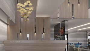 A modern reception area with a wooden reception desk labeled "RECEPTION," a unique chandelier, and a seating area with blue chairs. - Maralia Hotel (Nicosia)