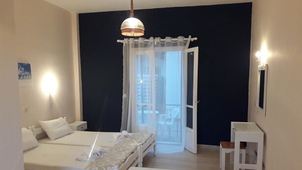 Ein Schlafzimmer mit zwei Betten, einem Balkon und einem kleinen Tisch.