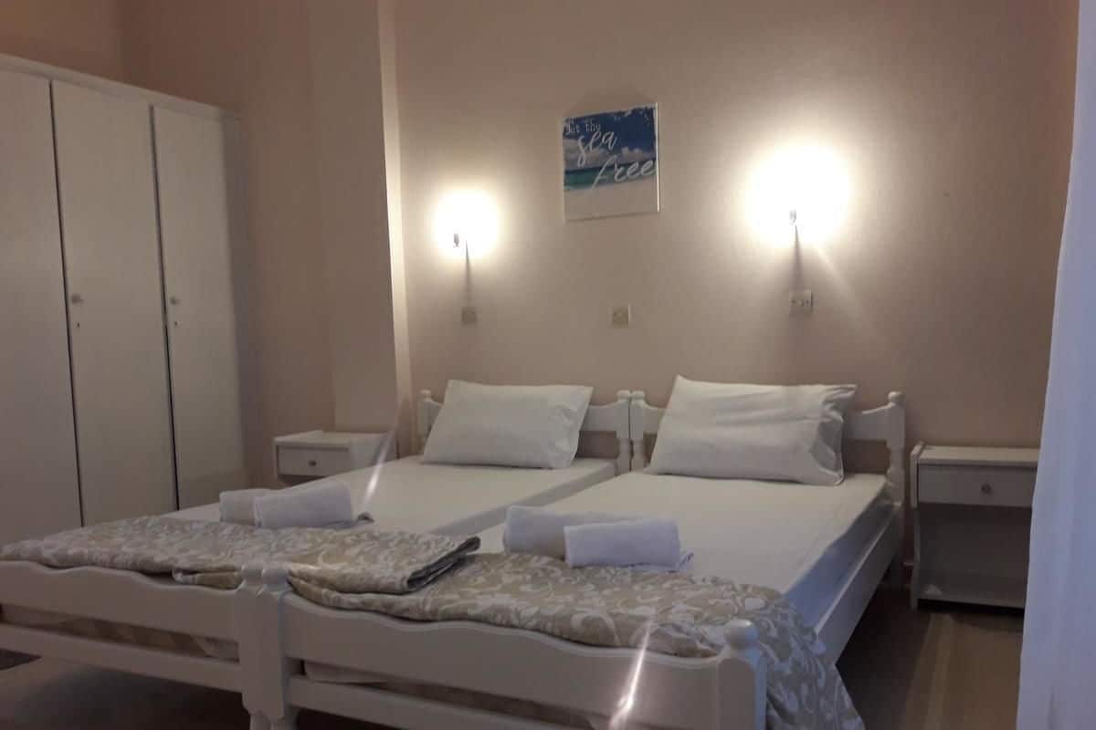 A bedroom with a double bed, two bedside tables, a wardrobe, and a wall-mounted light fixture.