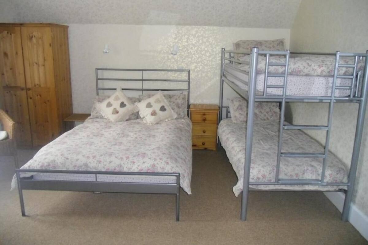 A bedroom with a single metal bed, a wooden wardrobe, and a dresser.