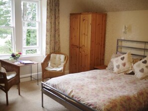 A bedroom with a bed, a wooden wardrobe, a chair, a small table, and a window with curtains. - The Ormidale Hotel (Isle of Arran)