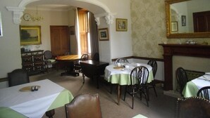 A dining room with a chandelier, a large mirror, and a fireplace. - The Ormidale Hotel (Isle of Arran)