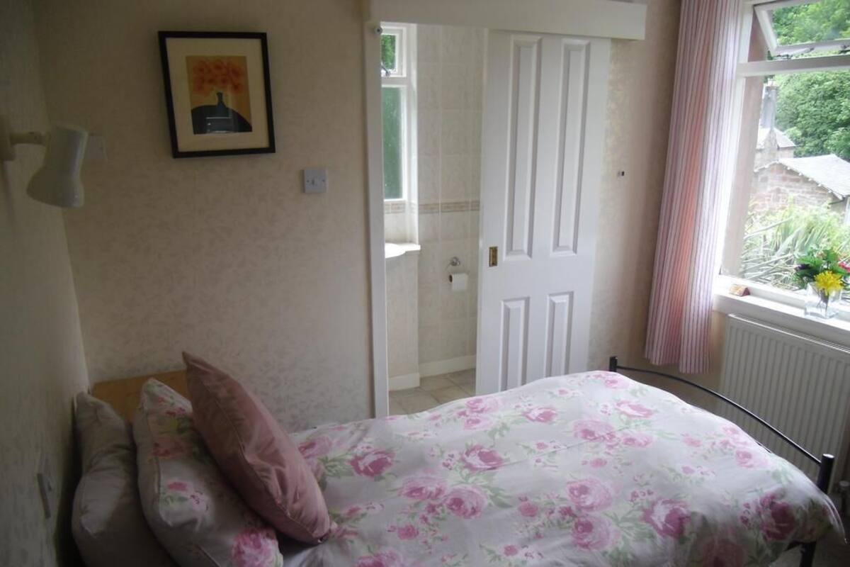 A bedroom with a bed, a door, a window with curtains, and a wall-mounted picture.