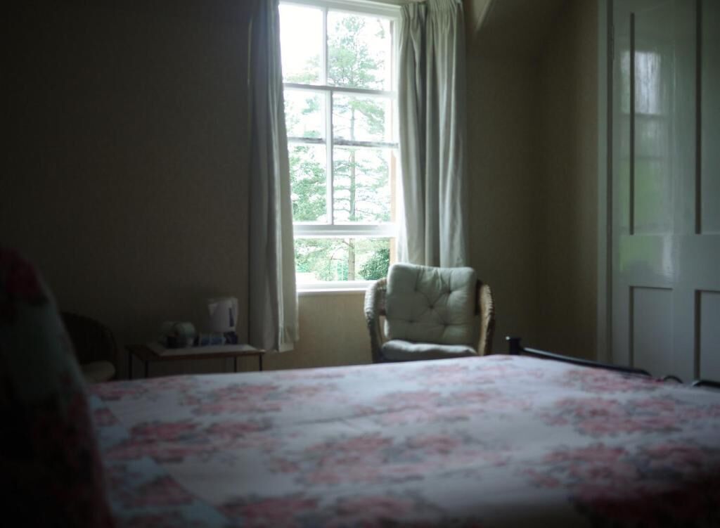 A bedroom with a bed, a chair, a window, and a door.
