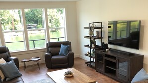 A modern living room with a sofa, armchairs, a coffee table, a TV, and a bookshelf. - CHARMING AND SPECTACULAR RIVERFRONT HOUSE, BEAUTIFUL IN ANY SEASON OF THE YEAR! (Leaburg)