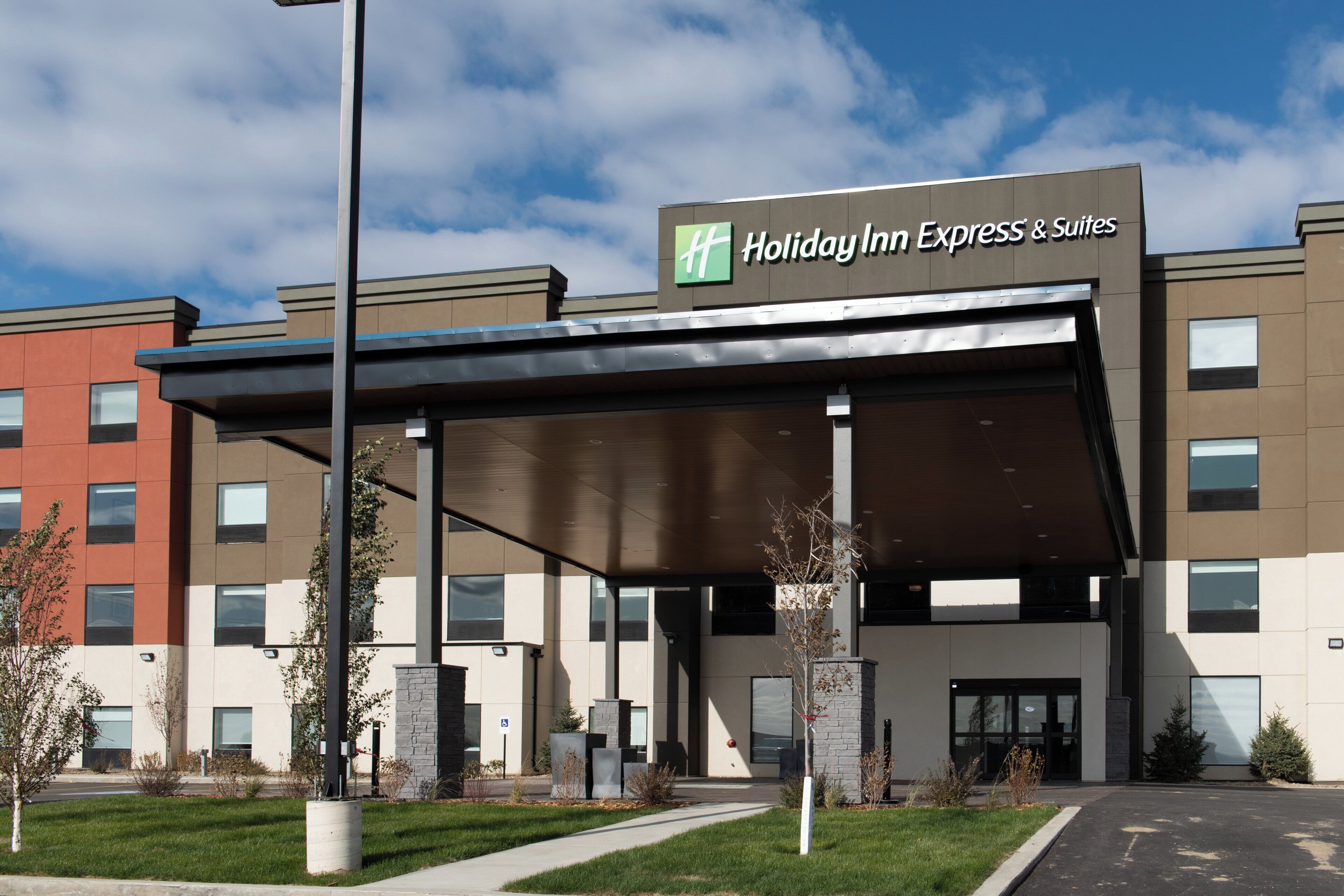 A Holiday Inn Express & Suites building with a covered entrance and multiple windows.