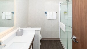 A modern bathroom with a white sink, a glass shower enclosure, and a wooden door. - Holiday Inn Express & Suites North Battleford by IHG (North Battleford)