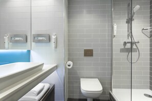 A modern bathroom with a white sink, toilet, and shower area.