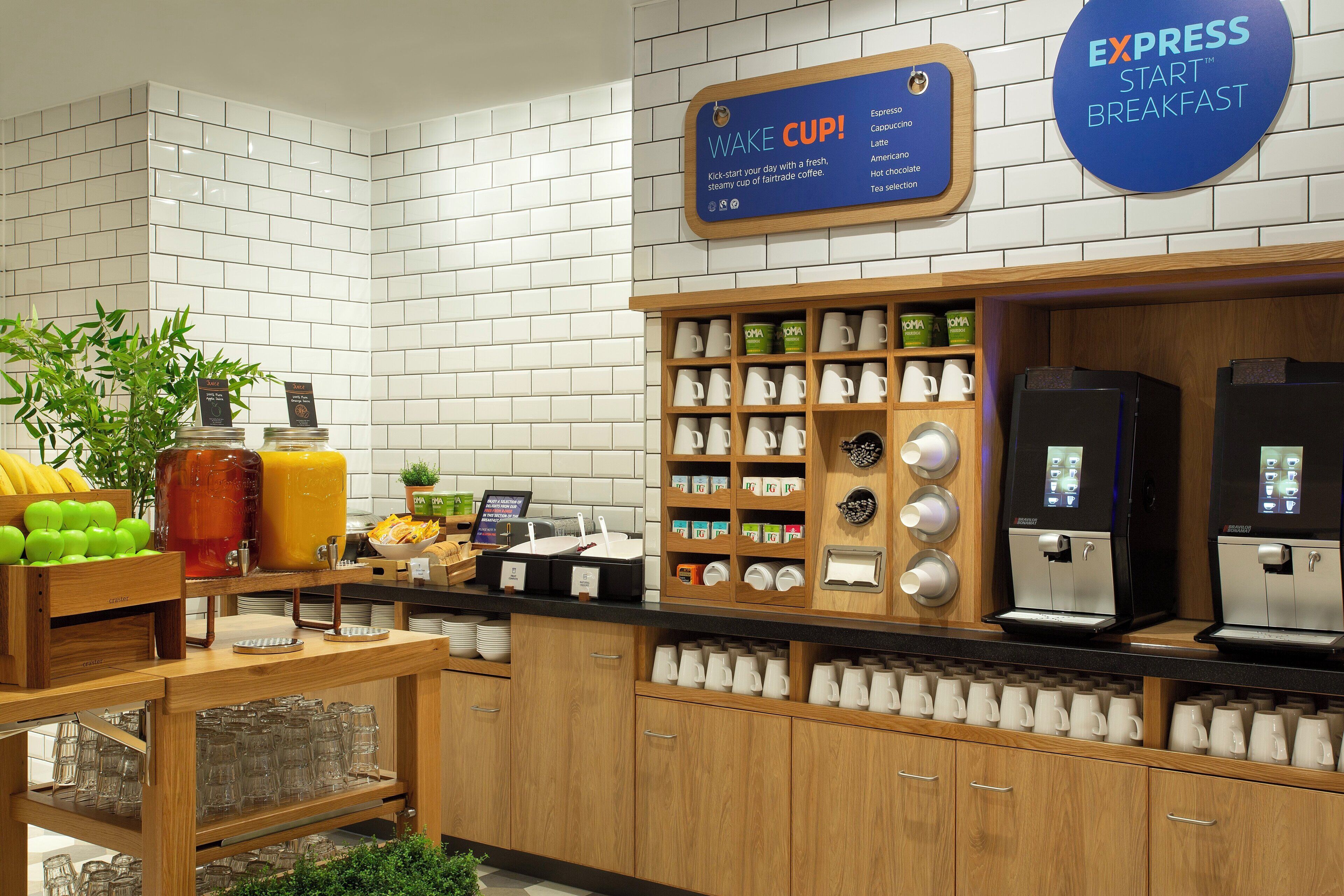 A breakfast area with a coffee station, a sign for 'Wake Cup,' and a variety of food items.