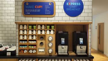 Una estación de café con un cartel que dice 'Wake Cup' y 'Express Star Breakfast', una máquina de café y una variedad de tazas y vasos.