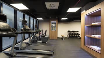 A gym with treadmills, a weight bench, and a rack of dumbbells.