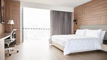A modern hotel room with a large bed, a desk, and a chair.