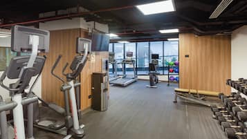 Un gimnasio con cintas de correr, elípticas, dispensador de agua y mancuernas.
