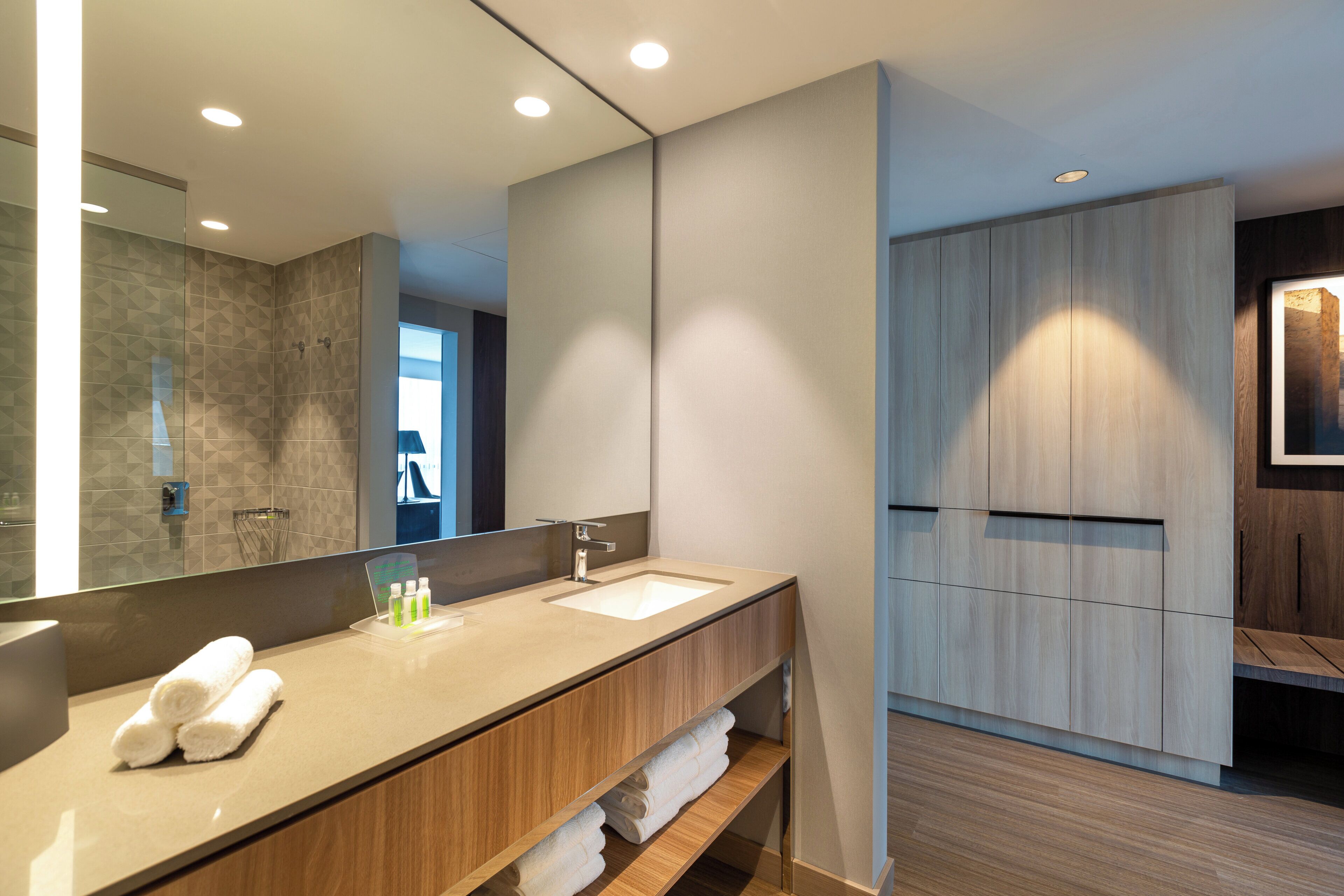 Un baño moderno con un espejo grande, un lavamanos y un mueble de tocador de madera.