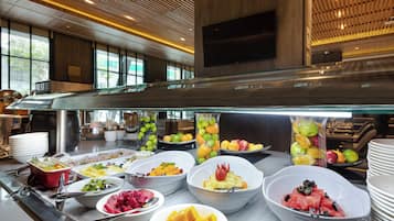 Un bufé con diversas frutas y verduras, incluyendo sandía, mango y uvas.