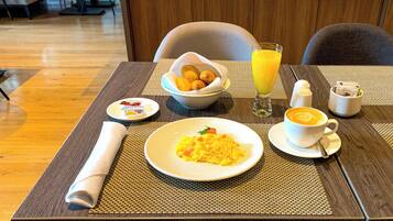 Una mesa de desayuno con platos de comida, un vaso de jugo de naranja y una taza de café.