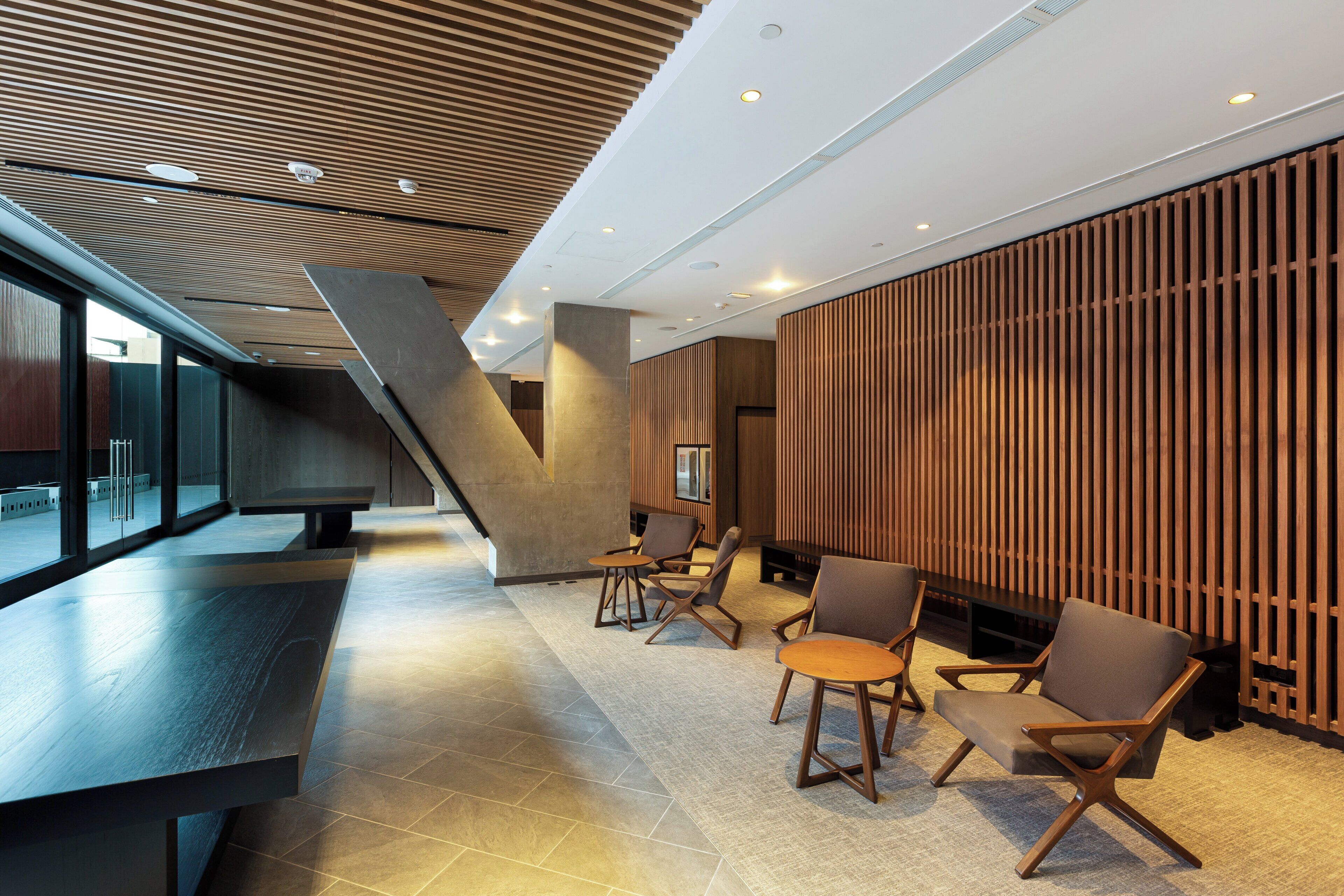 A modern interior with a sloped ceiling, seating area with chairs and tables, and a large window.