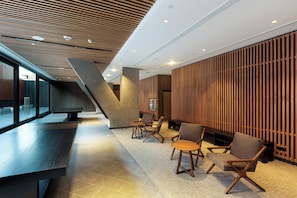 A modern interior with a sloped ceiling, seating area with chairs and tables, and a large window. - Holiday Inn Lima Miraflores by IHG (Lima)