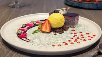 Un plato de postre con un pastel en capas, una bola de helado y detalles decorativos.