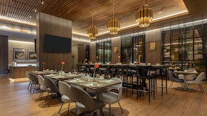A modern dining area with wooden flooring, black and grey chairs, and pendant lighting. - Holiday Inn Lima Miraflores by IHG (Lima)